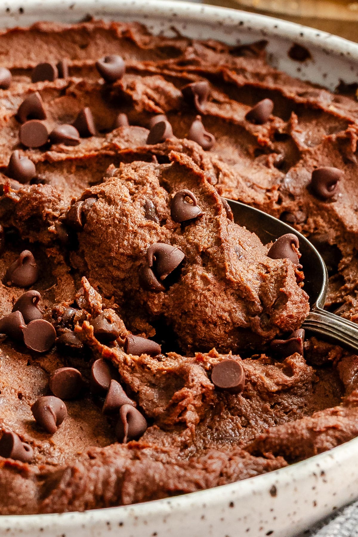 A spoonful of brownie batter dessert hummus in a speckled bowl.