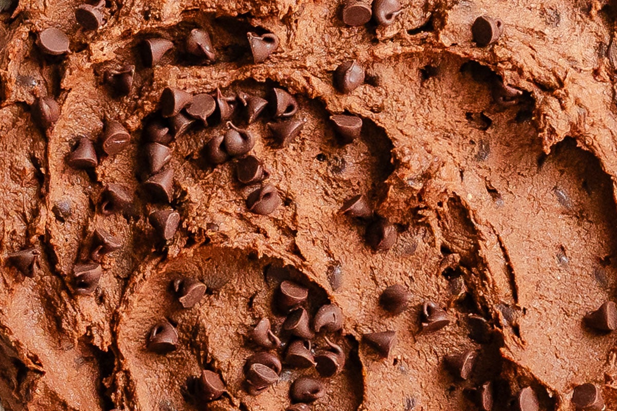 Close-up view of chocolate brownie batter hummus mixed with chocolate chips.