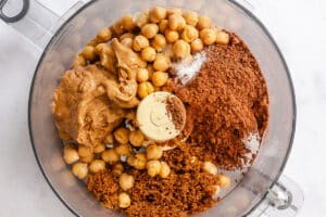 Chickpeas, peanut butter, cocoa powder, and brown sugar in a food processor bowl to make chocolate hummus.