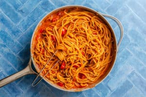 Spaghetti in a tomato sauce served in a stainless steel skillet.