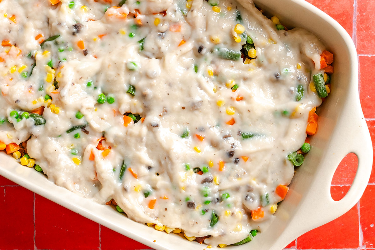 Casserole dish filled with a mixture of vegetables in a creamy white sauce.