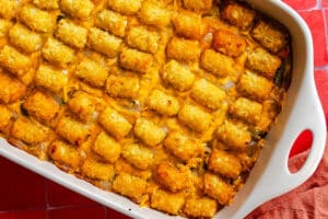 A rectangular baking dish filled with a tater tot casserole covered in melted cheddar cheese.