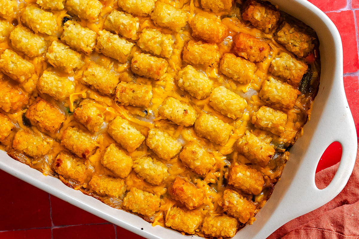 A rectangular baking dish filled with a tater tot casserole covered in melted cheddar cheese.